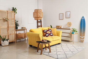 Interior of stylish living room with yellow sofa, houseplants and surfboard