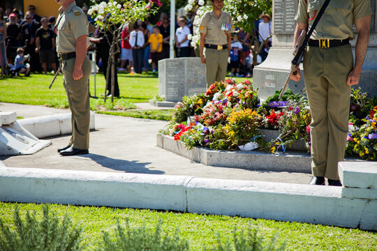 Australian soldiers standing around a cenotaph at an ANZAC Day service