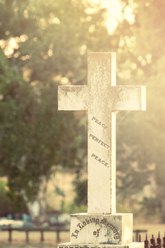 Sunlight hitting a cross on top of a gravestone