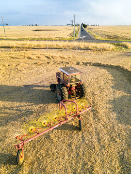 Looking down on a tractor and raking equipment sitting on farmland with smoke clouds on the horizon