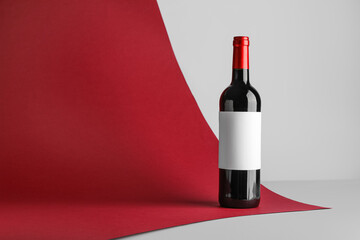 Bottle of red wine with blank label on color background
