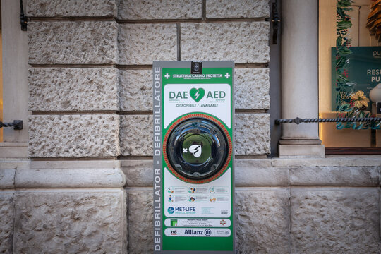 TRIESTE, ITALY - DECEMBER 17, 2024: Wall-mounted DAE/AED cabinet grants public access to automated external defibrillator, bilingual signage standing out against rugged stonework on a trieste street