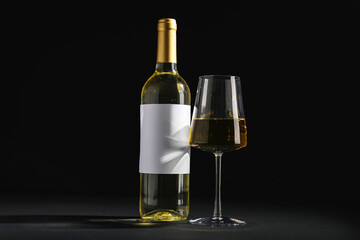 Bottle of wine with blank label and glass on black background