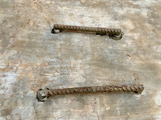 Two iron rods embedded in the grey cast floor, iron handle concept for drainage control tank