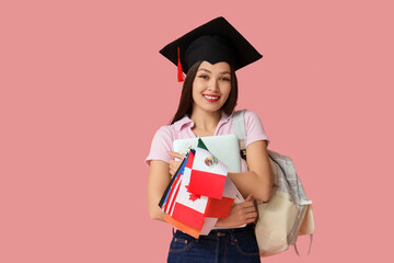 Female graduating student with flags of different countries and laptop on pink background