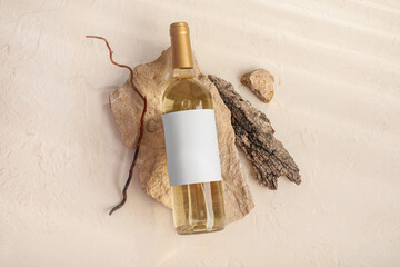 Bottle of wine with blank label, stones and twig on white grunge background