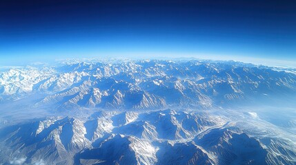 Aerial View of Snow Covered Mountain Range Under a Blue Sky