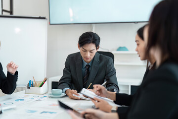 Focused Asian business executive leading a strategy meeting with colleagues in a modern conference room.