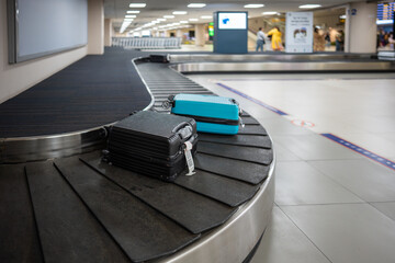 Loading luggage moving on baggage conveyor belt during post flight unloading. Travel bags advance toward claim area, passengers wait for returning items