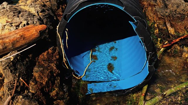 Large corrugated plastic drainage pipe discharging into a rocky shoreline or coastal area