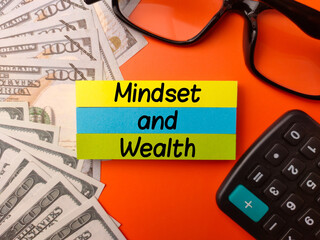Top view sticky note and banknotes with the word Mindset and Wealth on a orange background