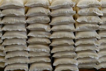 Many rows of plastic white sacks with goods are in big warehouse