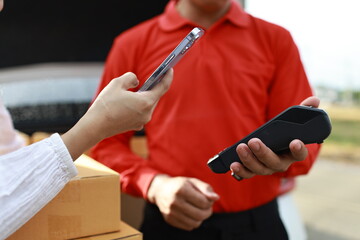 A courier delivers a package as a customer completes a payment. The e-commerce process connects shipping, retail, and efficient service.
