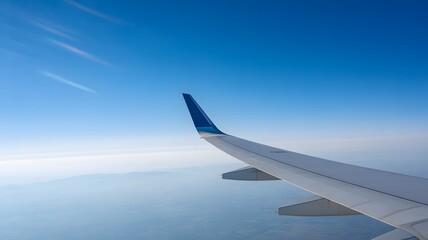 Obraz premium Airplane wing flying above clouds with clear blue sky view from window during daytime aerial travel perspective 