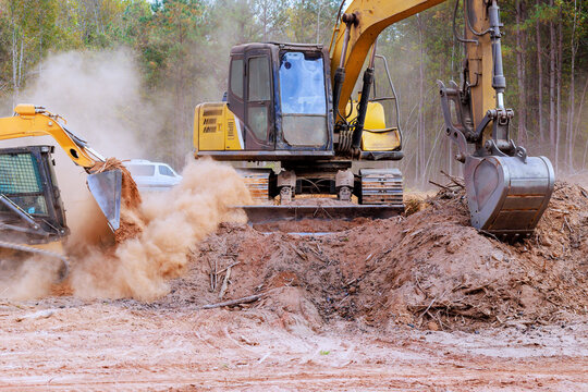 Excavators, bulldozers clear construction site, moving soil, debris on clear day.