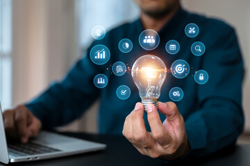 Hand chooses light bulb with business plan icons for goal and creative idea innovation or study...