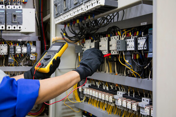 Fototapeta na wymiar Electrical service technician use electricity measuring tools equipment checking electric current circuit breaker terminal panel and cable wiring main power distribution board for maintenance system.