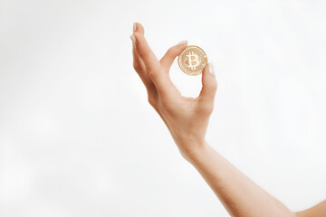 Woman's hand holding a golden Bitcoin coin isolated on white background