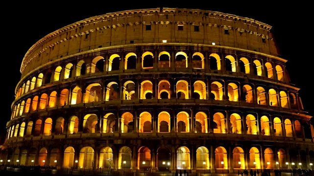 Illuminated amphitheater building at night featuring rows of arches and dark sky, ancient architecture, historic landmark, travel destination