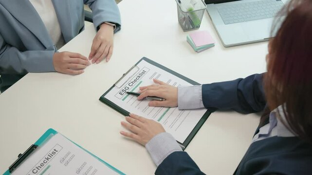 Asian female audit ESG risk check list paper form net zero waste supply chain vendor eco go green carbon credit control. Asia people woman give advice report prepare work review best practice process.