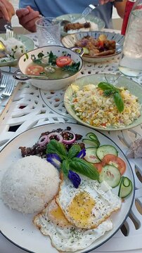 Eating together a sumptuous FIlipino breakfast spread featuring authentic local dish like chicken adobo, tinola, fried rice and bistek or karne frita