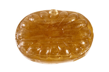 Close-up shot of a translucent, amber-colored hard candy with a ridged, oval shape and glossy surface, isolated on white background