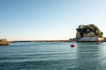 Peaceful winter morning panorama of Hirakata Fishing Port in Kitaibaraki, Ibaraki Prefecture, Japan &ndash; calm blue Pacific waters, small fishing boats and red marker buoys beneath a clear sky

