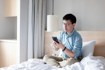 asian man using smart phone on bed