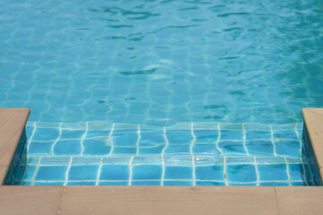 Clear Blue Swimming Pool with Steps and Sunlight Reflections. Related to vacation, leisure, or wellness. Relaxing summer vibe.