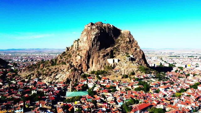 Aerial The Castle Of Afyonkarahisar On Rock Formation Against Clear Sky, Drone Flying Forward Over Houses In City