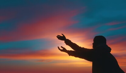 Silhouette of person reaching towards vibrant sunset sky.