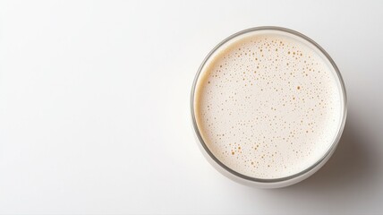 Top view of a glass filled with frothy, creamy drink on a white background drink glass creamy white