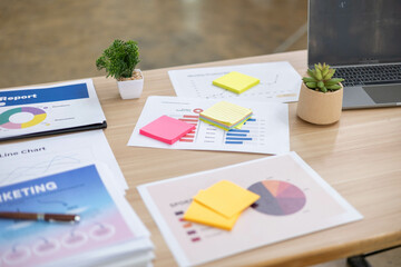 A desk with a laptop, calculator, and a stack of papers. The desk is cluttered and disorganized,...