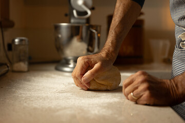Male hands kneading dough in the kitchen 