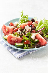Healthy and tasty salad with feta cheese, various tomatoes, olives, cucumber, onion and lettuce.	