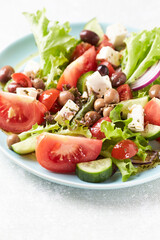 Healthy and tasty salad with feta cheese, various tomatoes, olives, cucumber, onion and lettuce.