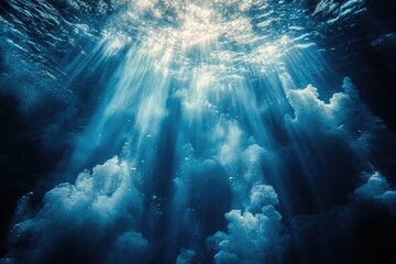 Obraz premium Underwater view of sunlight beams penetrating the deep ocean.