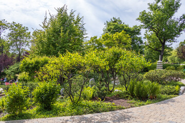  Curved walkway surrounded by trimmed bushes, trees, and a stone pagoda in the background in a Japanese-style park in Vienna, Austria.