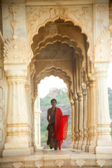Indian woman standing between arches and Pillars.
