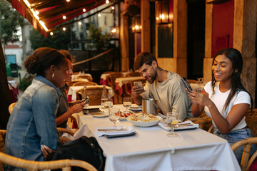 Friends using smart phones while having dinner at restaurant