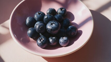 Fresh Blueberries in a Pink Bowl on a Light Surface with Soft Shadows and Natural Lights