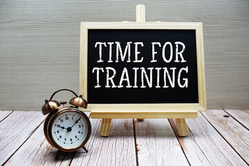 Time For Training text written on chalkboard with alarm clock on wooden background