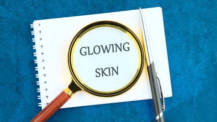 A magnifying glass focuses on the words glowing skin on a notepad. A pen rests beside the notepad, suggesting a discussion about skincare techniques and tips for a radiant complexion