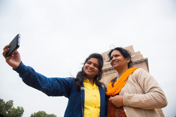 Tourist taking selfie with smart phone in front of India Gate, Delhi, India.