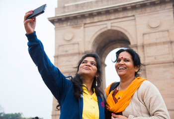 Tourist taking selfie with smart phone in front of India Gate, Delhi, India.