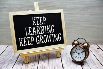 Keep Learning Keep Growing text written on chalkboard with alarm clock on wooden background