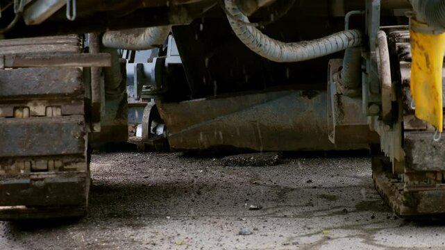 Close up of tracked construction machine, asphalt paver or road milling machine. metal tracks and hydraulic components are designed for heavy-duty roadwork.