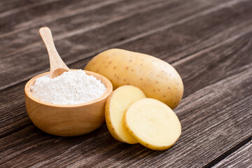 Potato starch (ground potato) and fresh potatoes with slice isolated on table background.