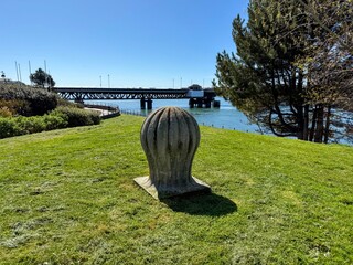 Stone bollard on waterfront grass with bridge backdrop