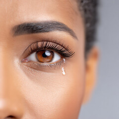 Fototapeta premium close-up photograph of a tear rolling down a cheek, symbolizing sadness, grief, or emotional pain,